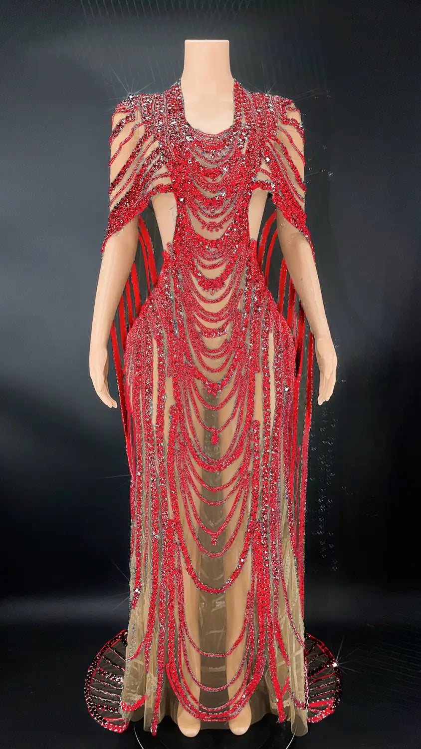 A dazzling red and silver red beaded celebrate crystal sequin evening gown featuring cascading strands of sequins and beads, sheer mesh panels, and a dramatic cape-like design.