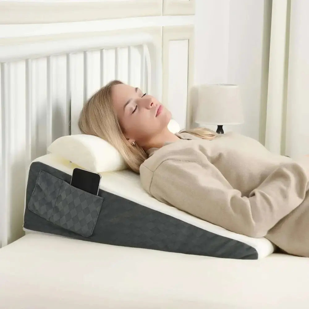 Gray and white wedge-shaped sleep apnea and acid reflux pillow with a textured pocket holding a smartphone