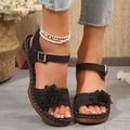 Black floral embellished chunky heel sandals with textured brown sole and adjustable ankle straps
