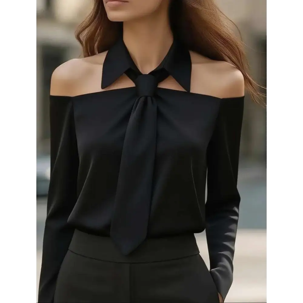 Black satin off-the-shoulder blouse with strap lapel design and prominent tied bow at the neckline