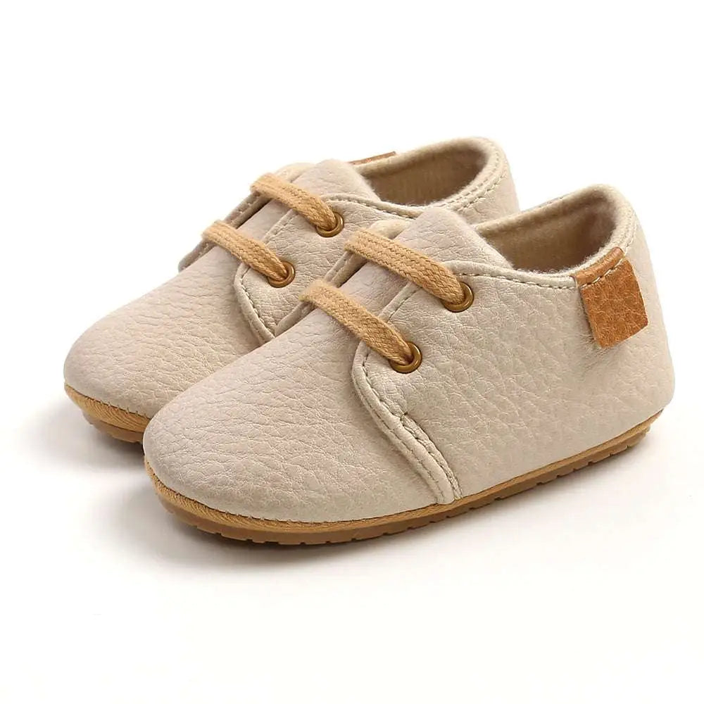 Beige leather baby casual shoes with tan laces and a textured matching patch for comfortable everyday wear