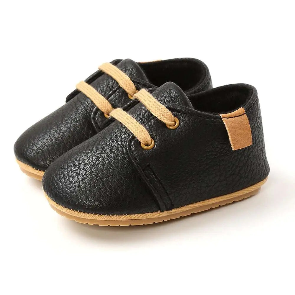 Beige leather baby casual shoes featuring black leather baby casual shoes with tan laces and matching heel tab