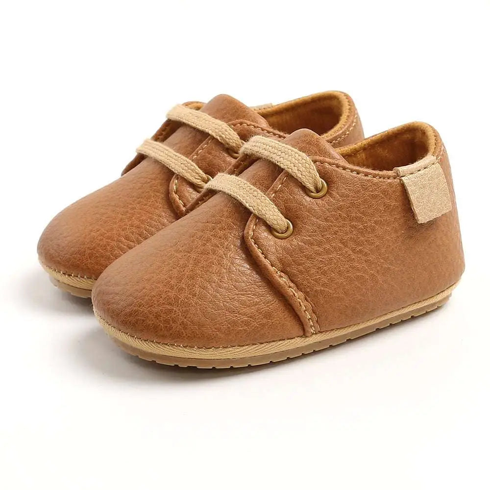 Beige leather baby casual shoes with tan lace-up design and soft rubber soles for comfortable wear