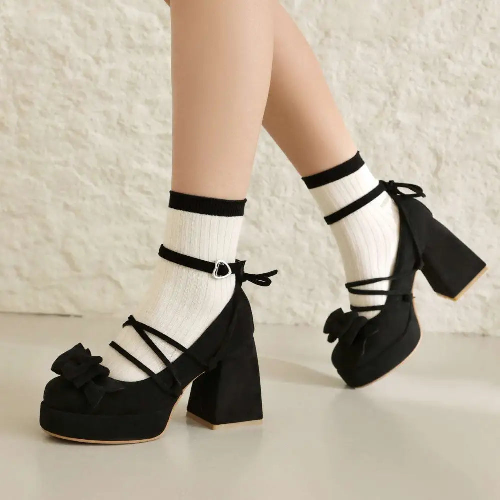Black platform lolita heels with chunky block heel, ankle strap, decorative bows, and suede-like material