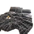 A plush dark gray faux fur throw blanket with chunky knit texture, a velvet blanket thickened for warmth and comfort