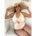 Beige ribbed one-piece swimsuit with halter neck paired with a wide-brimmed straw hat with woven texture and frayed edges