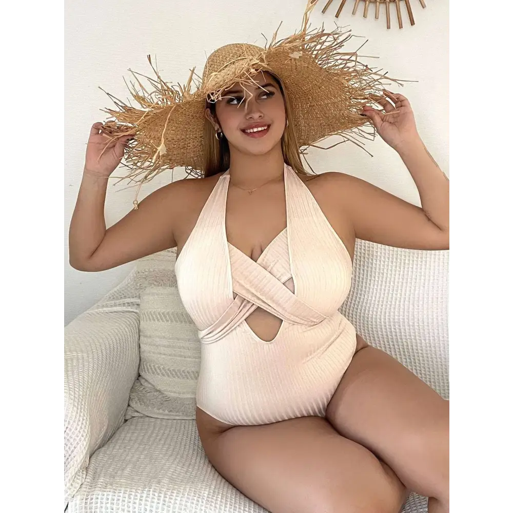 Beige ribbed one-piece swimsuit with halter neck paired with a wide-brimmed straw hat with woven texture and frayed edges