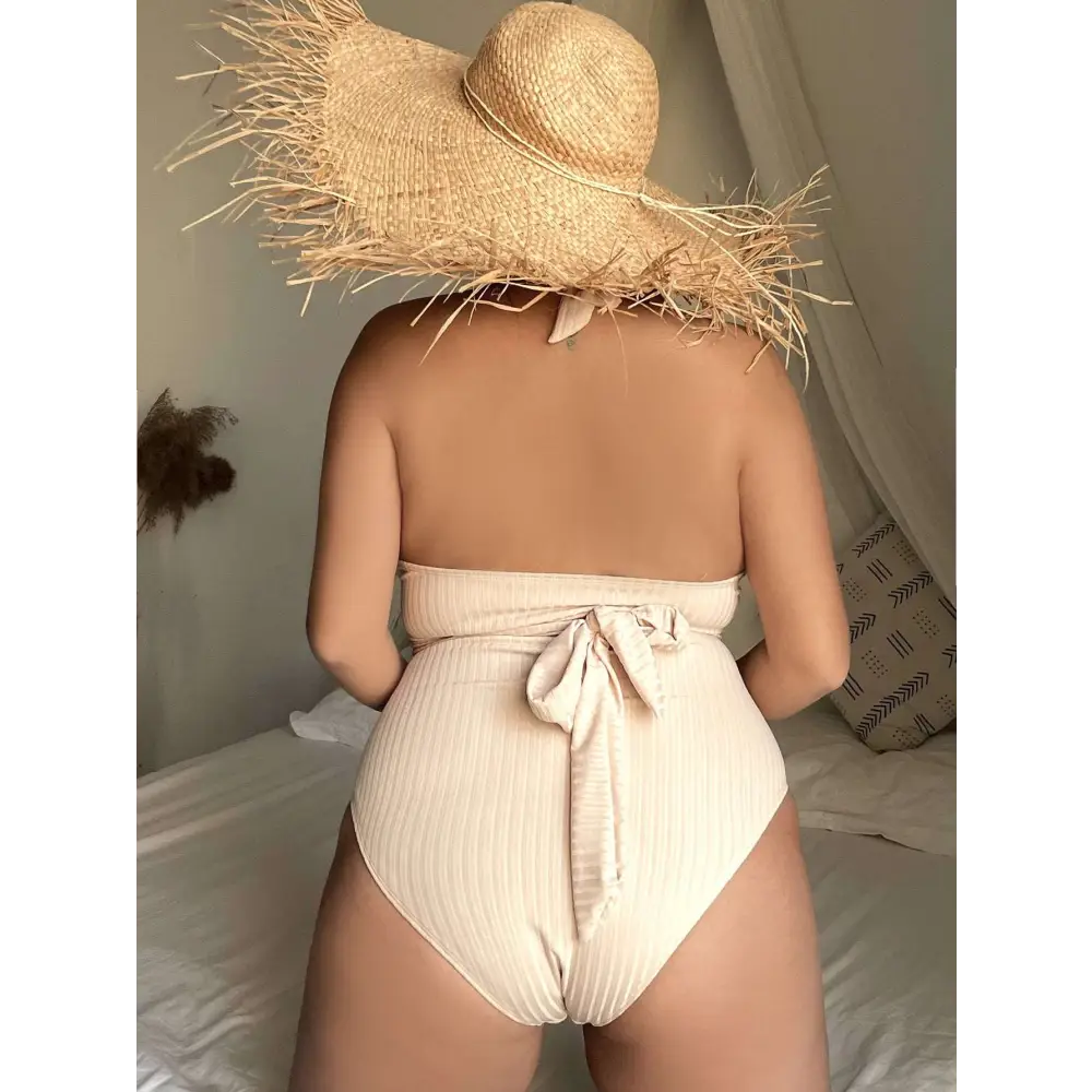 Beige ribbed one-piece swimsuit with halter neck and back tie detail shown from the back side