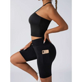 Black high-waisted bike shorts with side pocket holding smartphone paired with beige ribbed high waist workout set