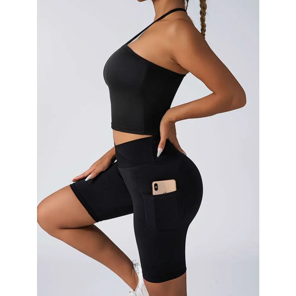 Black high-waisted bike shorts with side pocket holding smartphone paired with beige ribbed high waist workout set