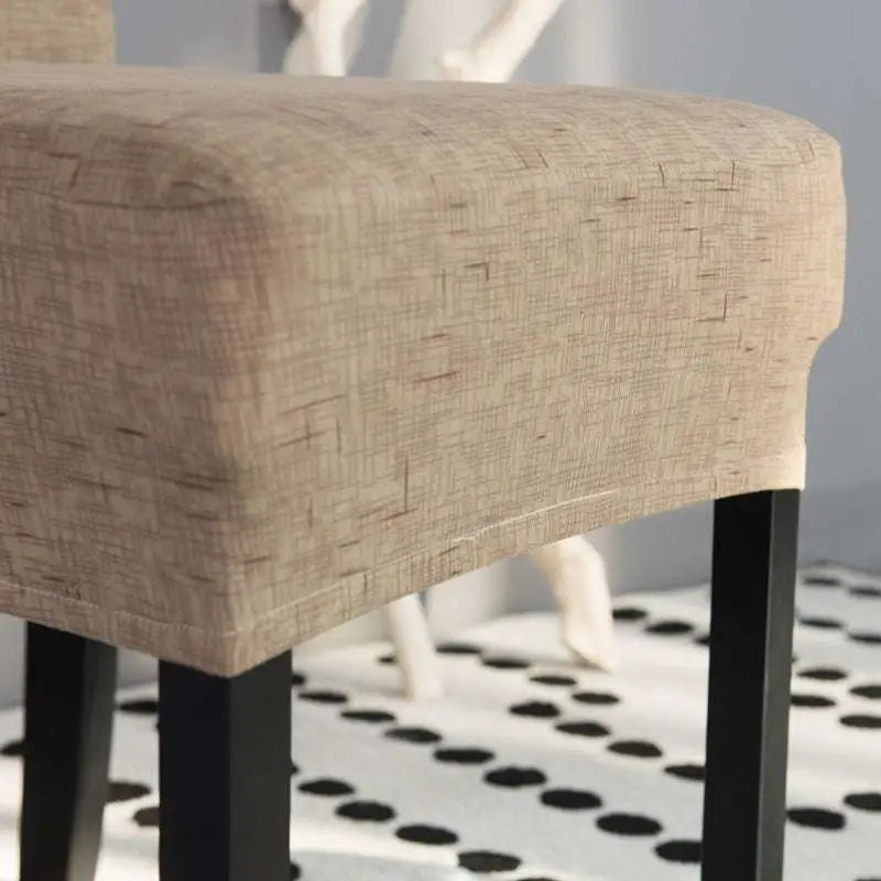 Beige textured universal chair cover on a fabric chair with black metal legs displaying key product features