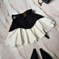Black and white two tone pleated mini skirt with black belt and gold c shaped buckle for waist tiered skirt style
