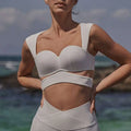 White structured sports bra with wide straps paired with beige yoga pants in sport coat fitness set for activewear