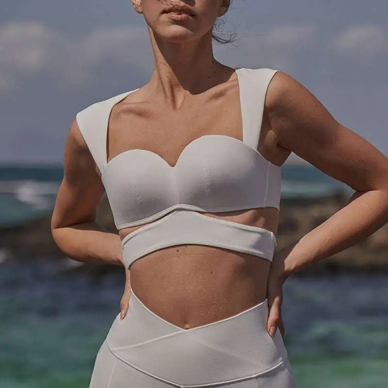 White structured sports bra with wide straps paired with beige yoga pants in sport coat fitness set for activewear