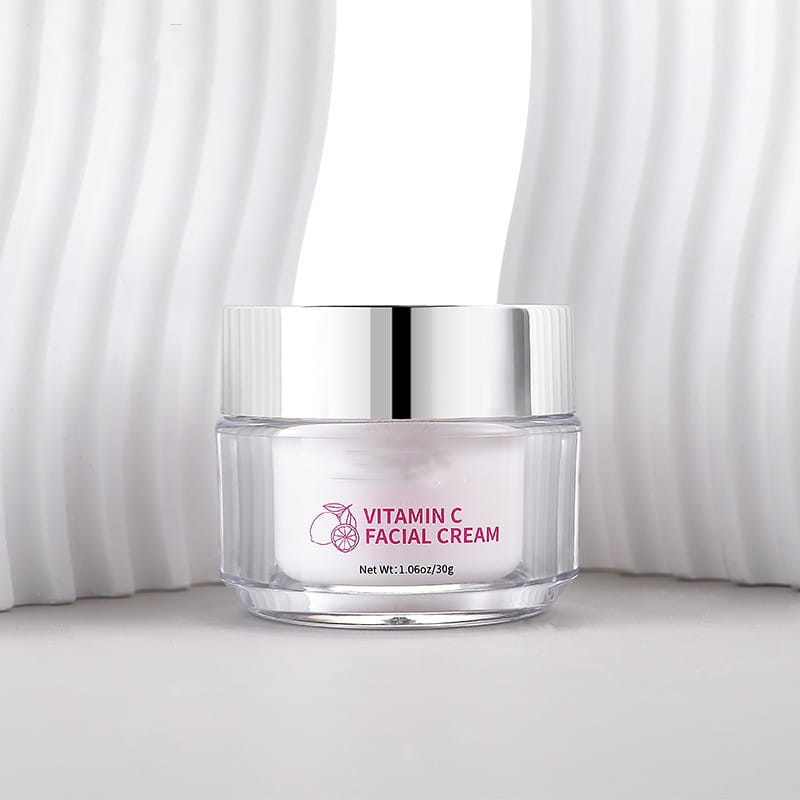 A clear glass jar with a silver lid contains white vitamin c brightening face cream labeled in pink text for brightening face cream 30g.