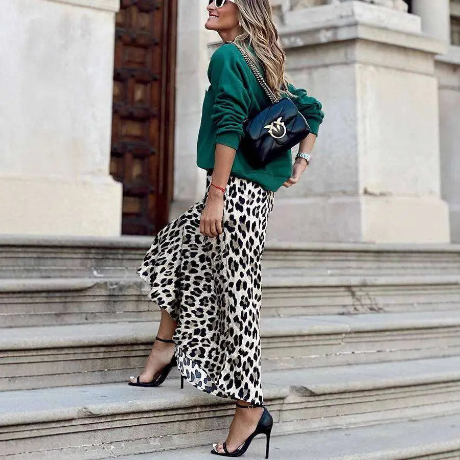 Black leather crossbody bag with gold-tone logo and chain strap paired with leopard print elastic a line skirt with flared hem
