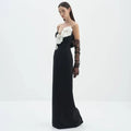 Black backless bandage gown featuring white floral appliqués on a bandage chest paired with sheer ruched black gloves