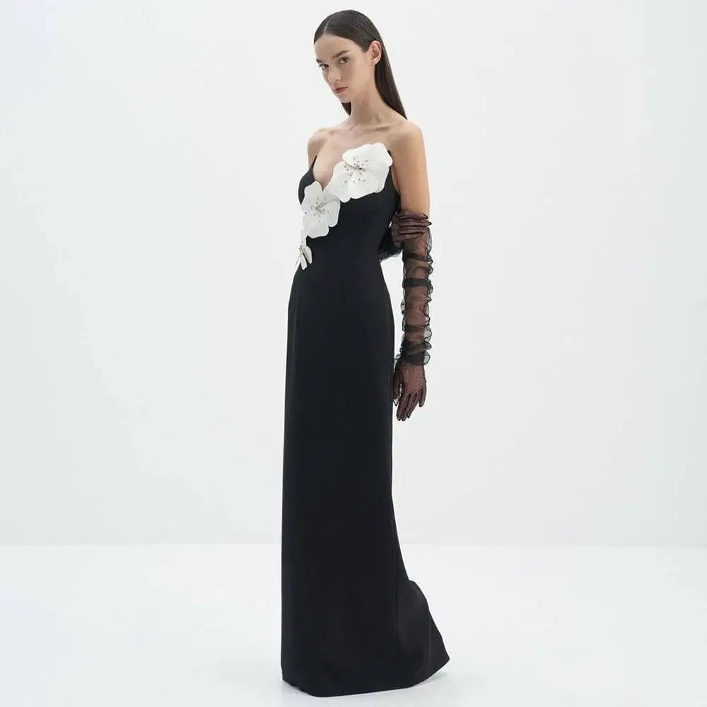 Black backless bandage gown featuring white floral appliqués on a bandage chest paired with sheer ruched black gloves