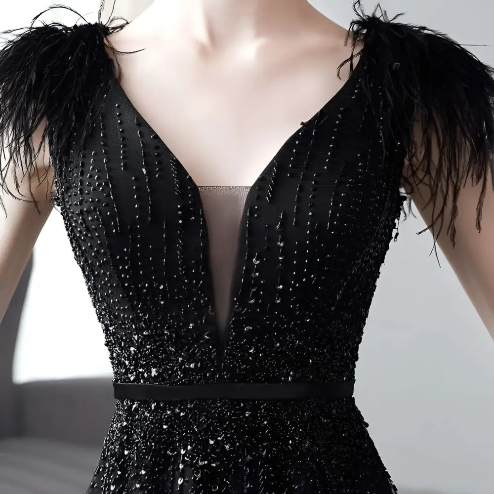 Black double shoulder evening dress featuring feathered shoulder accents and a beaded sequined bodice