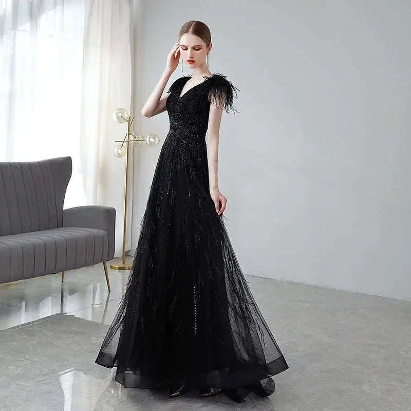 Elegant black double shoulder evening dress featuring feathered shoulder accents and sparkling sequin embellishments