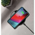 A sleek green phone case on a black glossy 15w smooth wireless charger showing 100% charged on screen