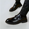 Black glossy business casual leather loafers with a prominent buckle strap and patent leather finish