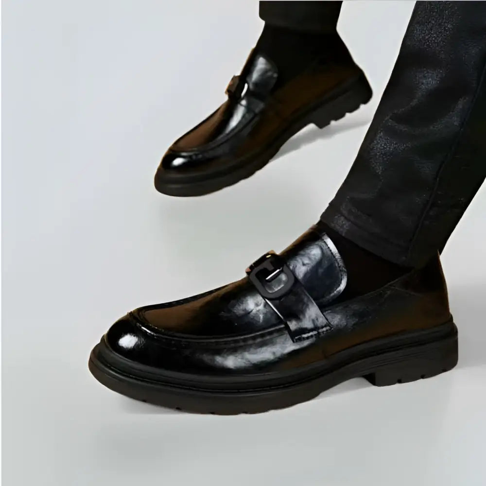 Black glossy business casual leather loafers with a prominent buckle strap and patent leather finish