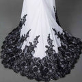 White slim mermaid tail wedding dress with intricate black lace detailing along the hemline