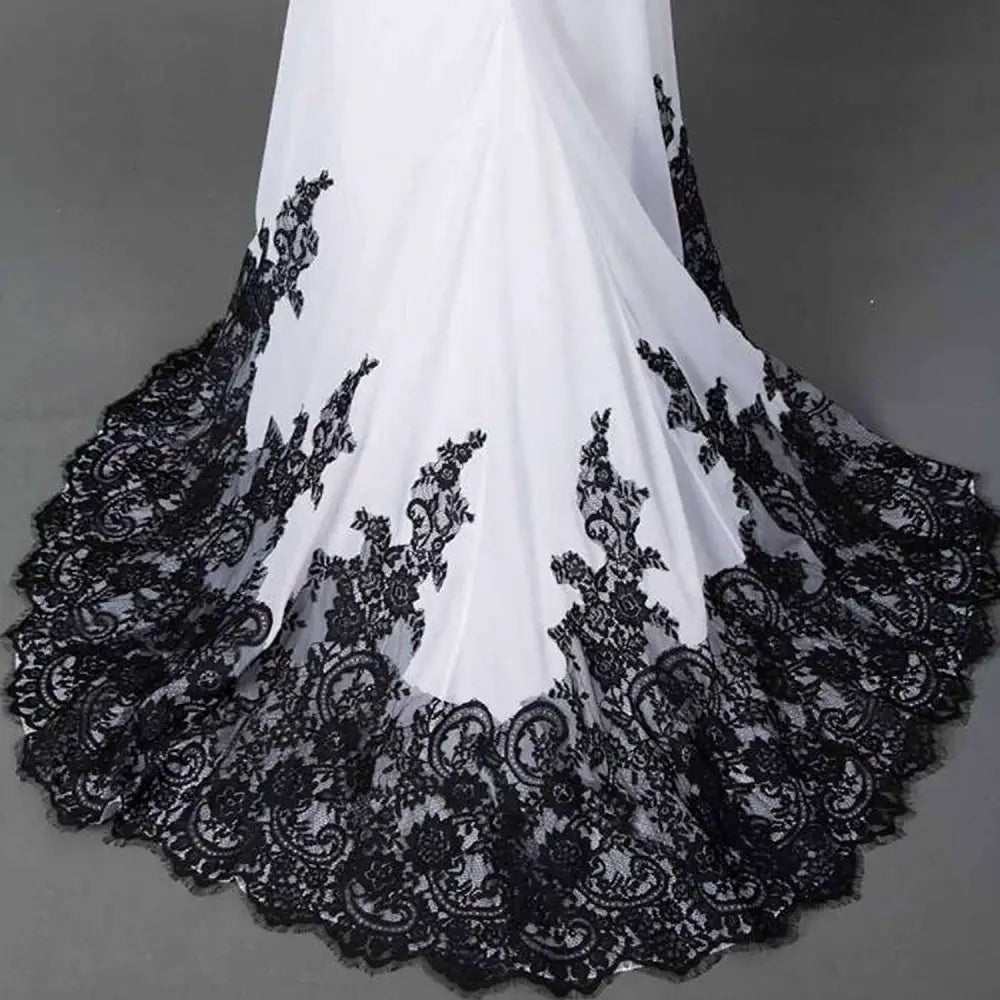White slim mermaid tail wedding dress with intricate black lace detailing along the hemline