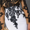 A slim mermaid tail wedding dress with a white fitted bodice adorned by intricate black lace appliqué and mesh detailing
