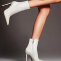 White leather stiletto ankle boots with sleek pointed toe and slender high heel featuring zipper closure