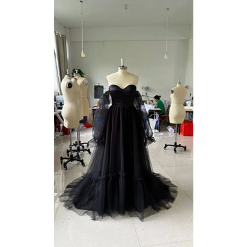 Black long sleeve transparent lace wedding dress featuring a black strapless ball gown with sheer puff sleeves and layered tulle skirt