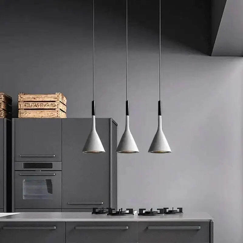 Three black minimalist funnel pendant lights with matte white conical shades hang above a gray kitchen counter