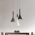 Three modern funnel pendant lights with sleek black minimalist funnel shades suspended above a wooden table