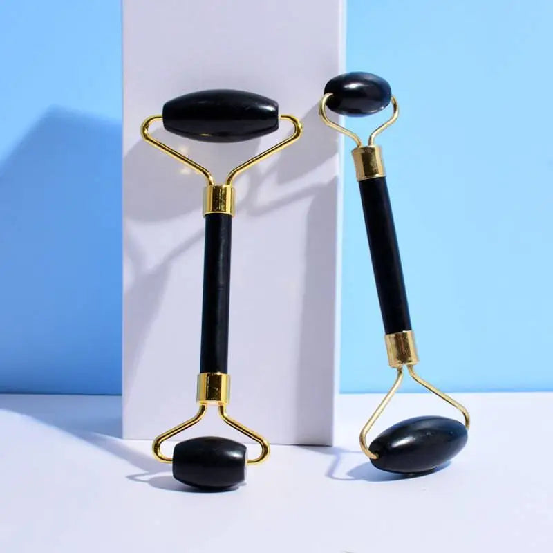 Black obsidian beauty face care massage jade roller with gold-toned metal handles and accents for skincare use