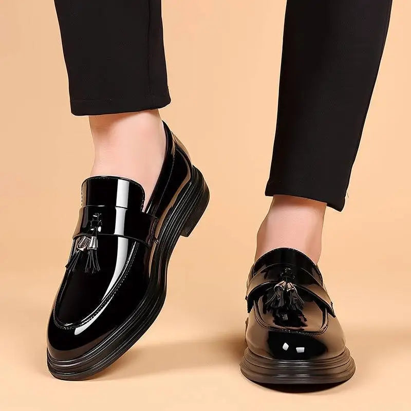 Black patent leather tassel loafers with a glossy finish and chunky sole for business formal wear