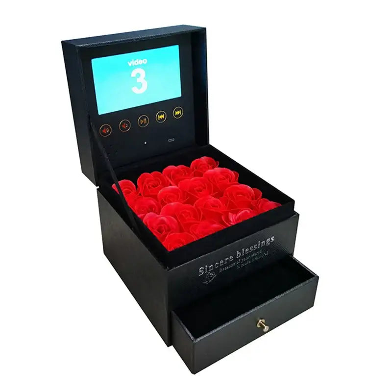 Black rectangular tech accessory power bank with built-in screen displaying video playback and vibrant red artificial roses inside featured in the best gadgets and tech accessories for 2026.