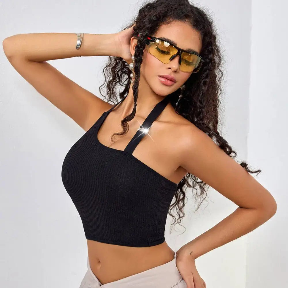 Black ribbed solid color shoulder vest featuring a low cut one shoulder design with a square neckline and crossed straps