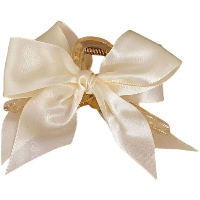 Cream satin female graceful bow grip with translucent gold-toned claw mechanism for elegant hair styling