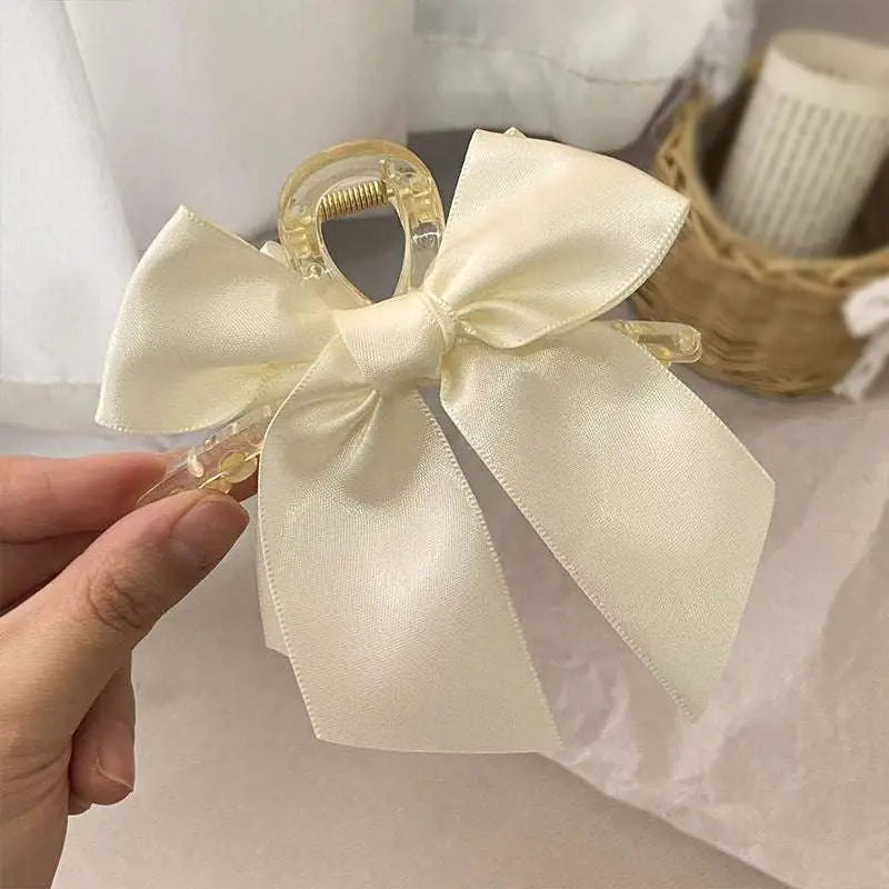 Black satin satin female graceful bow grip shark clip with a delicate cream satin bow on a transparent plastic clip