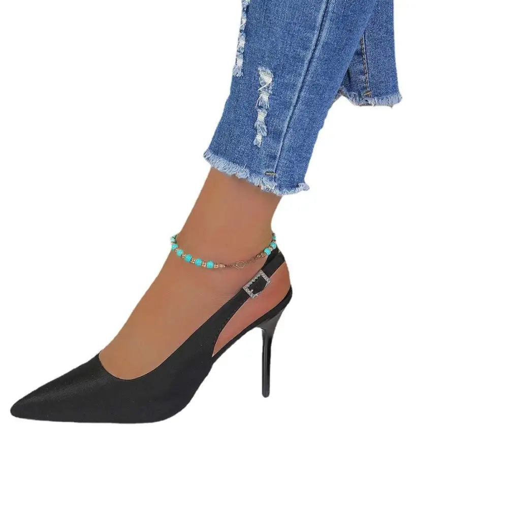 Black satin high heel sandals with pointed toe, sleek ankle strap, and silver buckle in a closed toe design