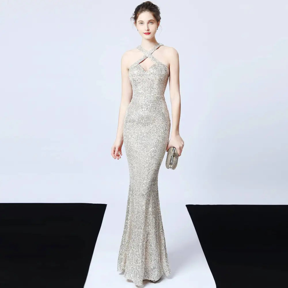 Silver sequined mermaid dress with halter neckline and crisscross straps featuring a long skirt length
