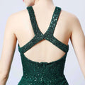 Emerald green sequined mermaid dress with backless crisscross strap design and halter neckline shown from back side