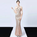 A shimmering rose gold sequined mermaid dress with a halter neckline and cross-back detail in long skirt length