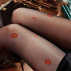 Translucent black sheer snagging resistant sock leggings with vibrant orange lipstick print and lettering design