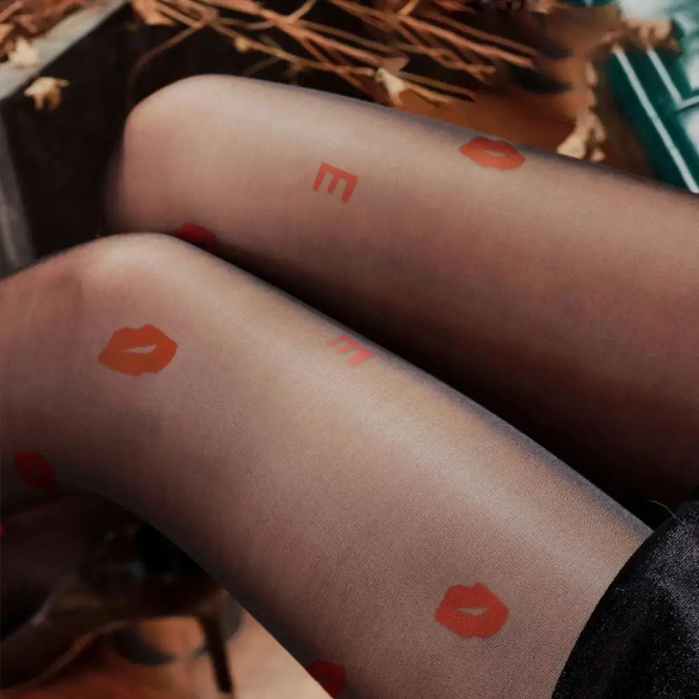 Translucent black sheer snagging resistant sock leggings with vibrant orange lipstick print and lettering design