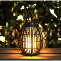 Black wrought iron lantern with warm glowing light inside solar retro patio woven rattan lantern design