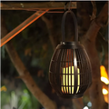 Black solar retro patio woven rattan lantern featuring a black wrought iron woven cage and glowing candle inside