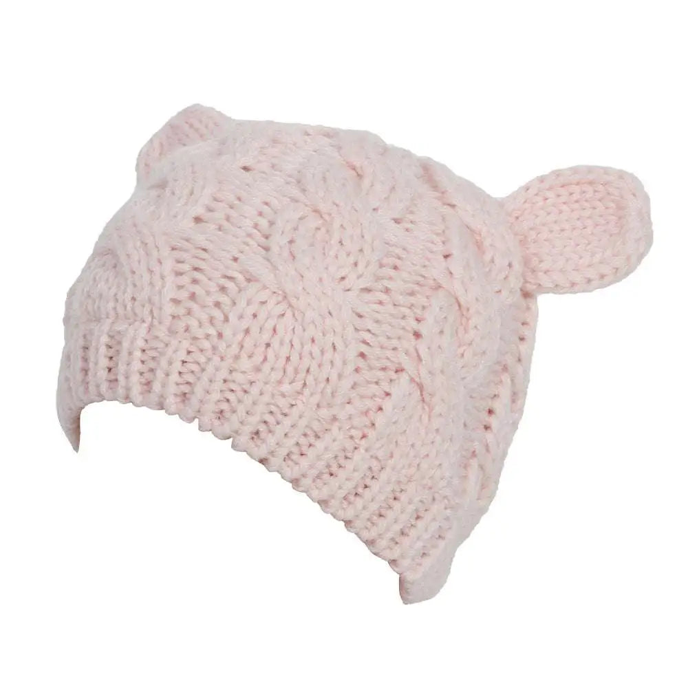 A soft pink knitted cat ear beanie with textured cable pattern and plush ear-like appendages in knit material