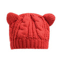 A vibrant red knitted beanie with a cable-knit pattern and two soft rounded bear ears, different from black textured cute knitted cat ear beanie